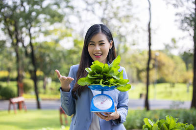 Portrait of a smiling young woman standing against plants