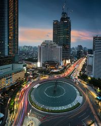 High angle view of illuminated street amidst buildings in city against sky