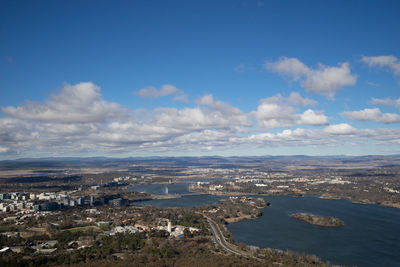 Aerial view of city by sea against sky