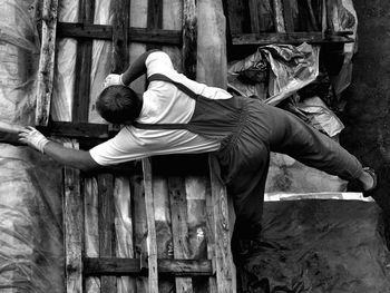 Directly above shot of man arranging wooden palettes on tarpaulin