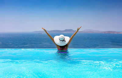 Rear view of woman in swimming pool against sea