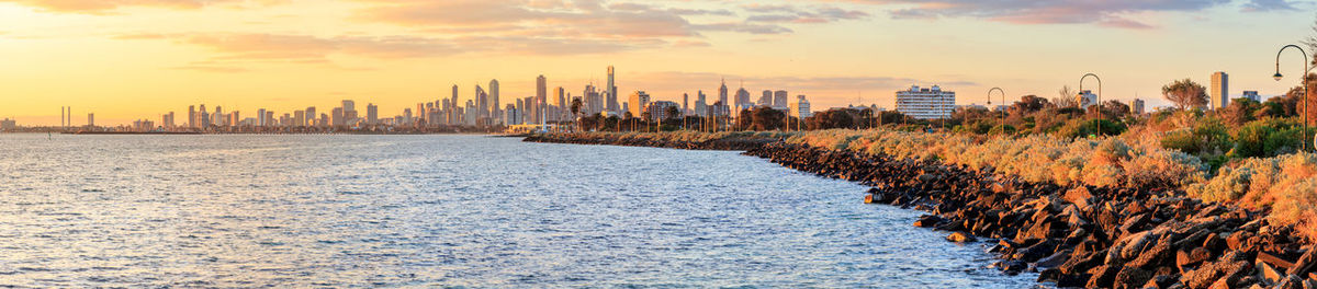 Panoramic view of sea and buildings against sky during sunset