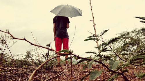 Rear view of woman standing on field against sky