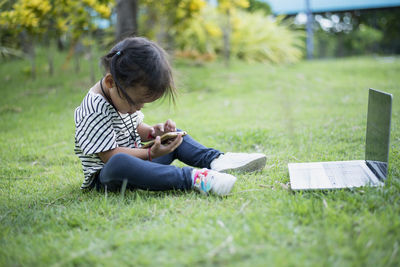 Woman using digital tablet while sitting on field