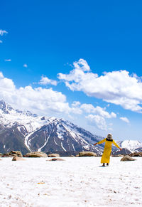 Rear view of woman standing on snowcapped mountain against sky