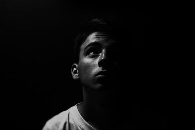 Portrait of teenage boy against black background