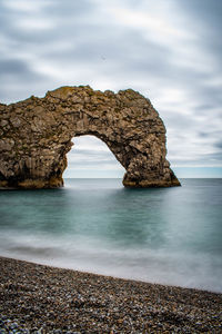 Rock formation on beach against sky