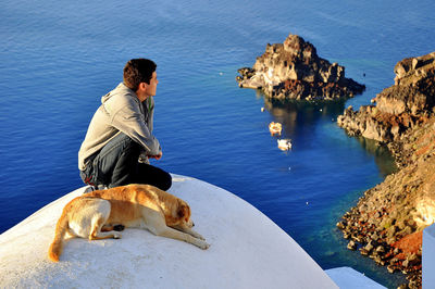 Full length of man with dog sitting by sea