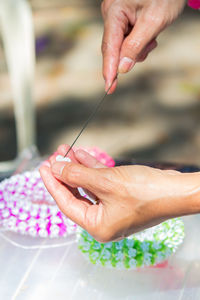 Cropped hands of woman making floral garland