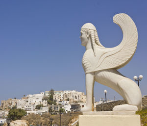 Low angle view of statue against building against clear blue sky