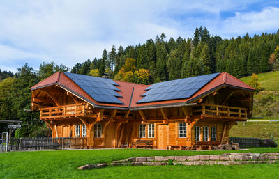 House on field by trees against sky