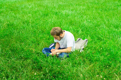 Man writing on book while sitting at grassy field