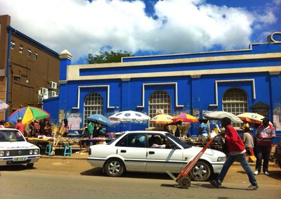 People on city street against cloudy sky