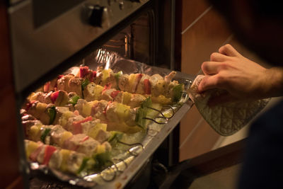 Cropped hand of man preparing food in oven at home