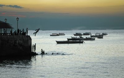 Silhouette boats in sea against sky during sunset