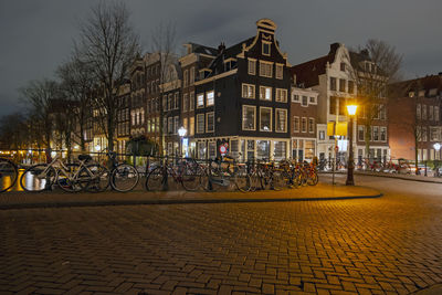 Bicycles on street by illuminated buildings at night