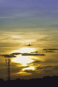 Low angle view of silhouette airplane flying against sky during sunset