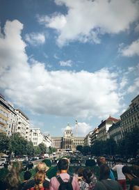 Group of people in city against cloudy sky