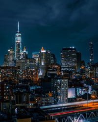 Illuminated modern buildings in city against sky at night