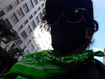 Close-up of man wearing sunglasses against buildings in city