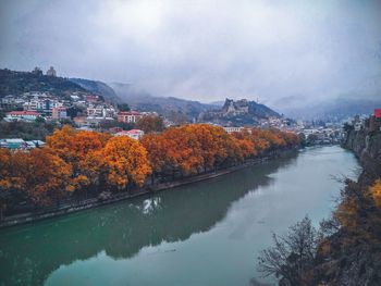 Scenic view of lake by buildings against sky during autumn