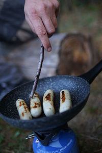 Preparing egg sausage on a frying pan with a camping gas stove at outdoor camp.