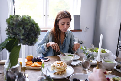 Couple having food at table against window