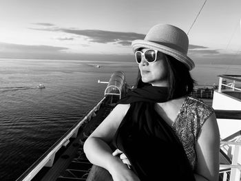 Woman wearing sunglasses standing in boat against sky