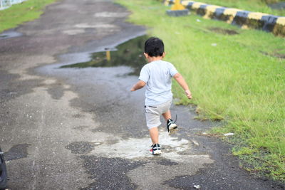 Rear view of boy running on road