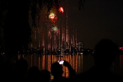 Firework display in city against sky at night