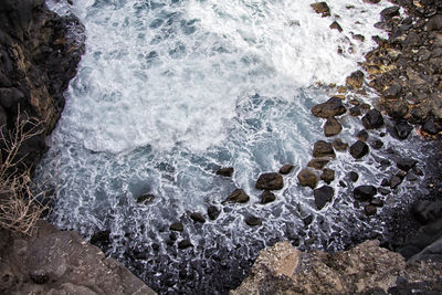 High angle view of waves splashing on rocks