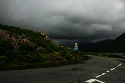 Road leading towards mountain against stormy sky in peak district, england, united kingdom 
