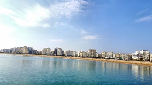 City buildings by river against sky