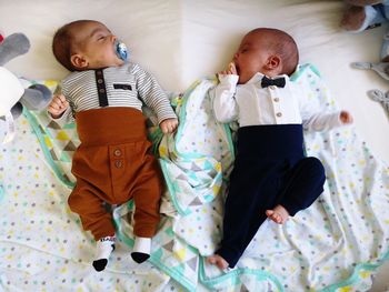 Directly above shot of newborn brothers lying on bed