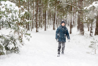 Front view of child boy in winter forest in snowstorm. kid on snowy winter background. actively 