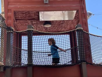 Child running behind rope net playground high up from below