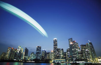 Light trail in sky over illuminated city