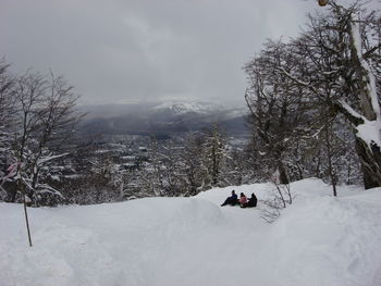 Man skiing on snow covered trees against sky