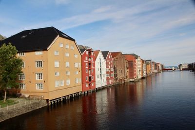 Buildings by river against sky