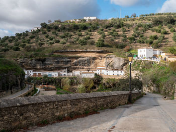 Road amidst trees and buildings against sky