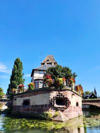 Building by river against clear blue sky