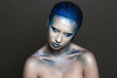 Close-up of woman wearing make-up against black background