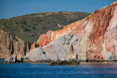 Scenic view of rocky mountain by sea against clear sky