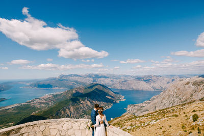 Rear view of woman standing on mountain against sky