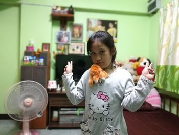 Close-up of girl showing peace signs at home