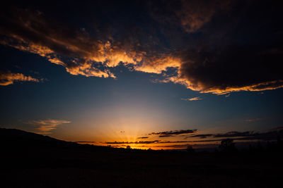Scenic view of silhouette landscape against dramatic sky during sunset