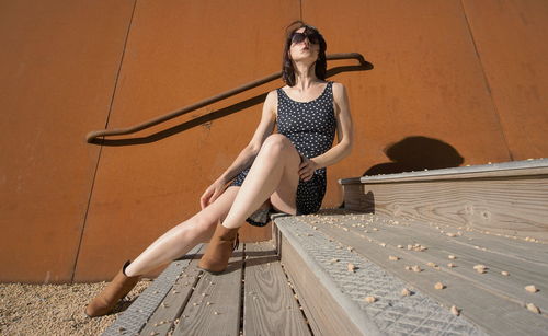 Low angle view of mid adult woman sitting on steps during sunny day