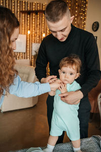 Mom and dad put on clothes for the child. high quality photo