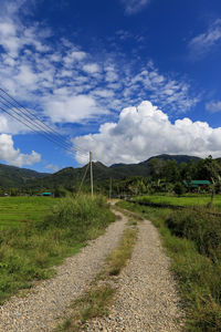 Road amidst field against sky
