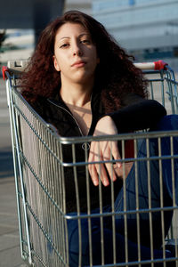 Portrait of woman sitting in shopping cart outdoors